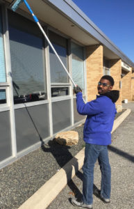 young man cleaning windows at an office building