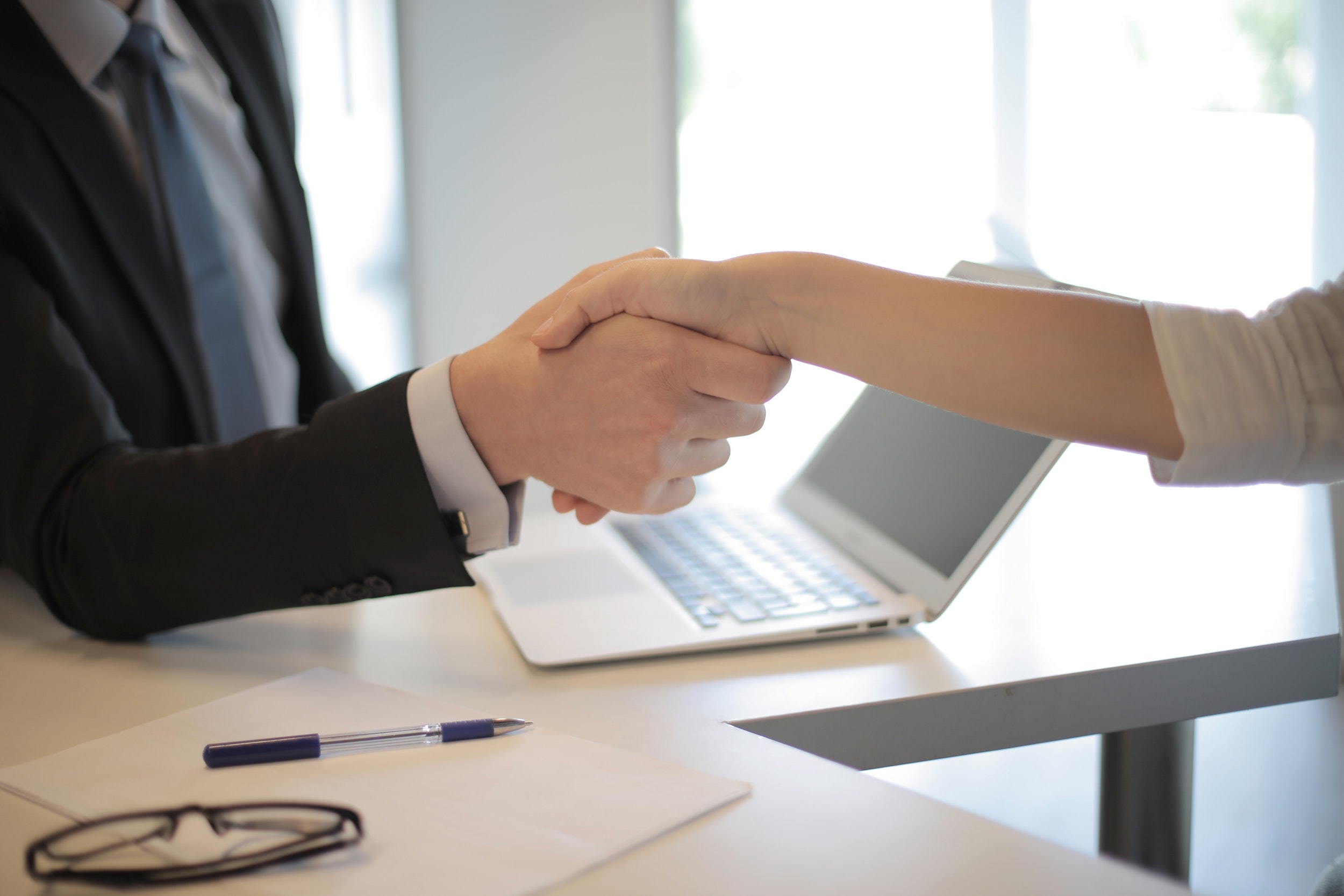 man and woman in office shaking hands across table